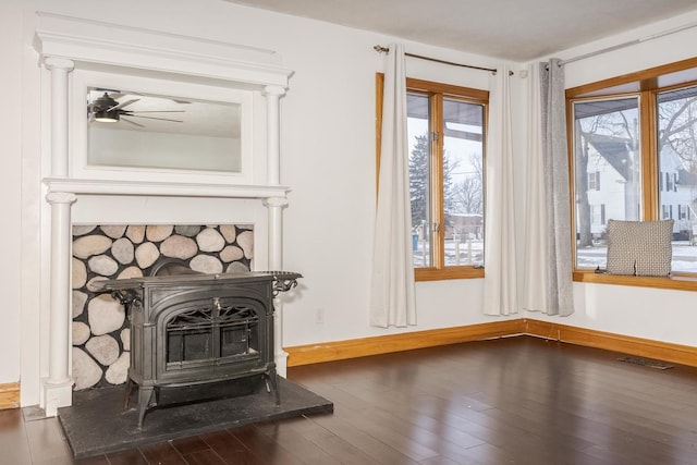 interior details with hardwood / wood-style flooring, ceiling fan, and a wood stove