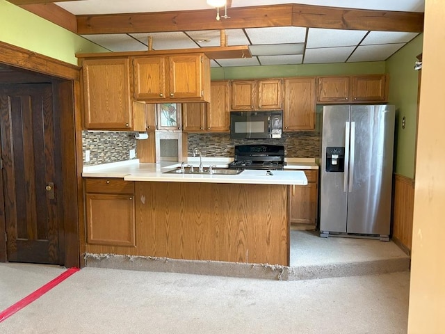 kitchen with tasteful backsplash, sink, stainless steel fridge, range, and kitchen peninsula