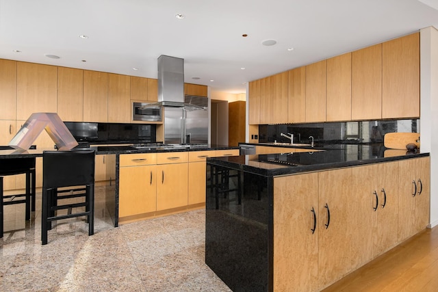 kitchen featuring built in appliances, decorative backsplash, island range hood, and dark stone countertops