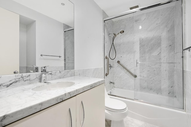 full bathroom featuring vanity, bath / shower combo with glass door, and toilet