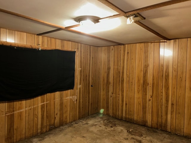 spare room featuring wooden walls and concrete flooring