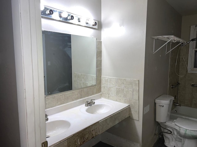 bathroom with tiled shower / bath combo, double sink, and toilet