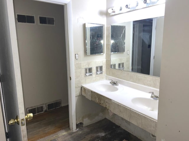 bathroom with hardwood / wood-style floors, double sink, and tile walls