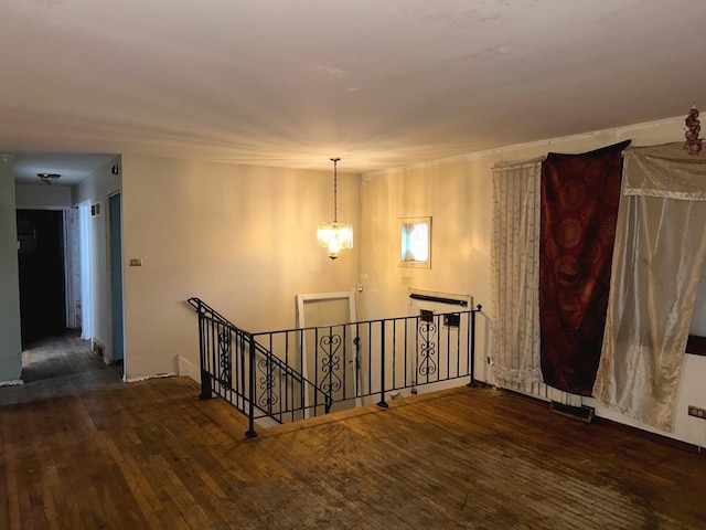 spare room featuring an inviting chandelier and dark wood-type flooring