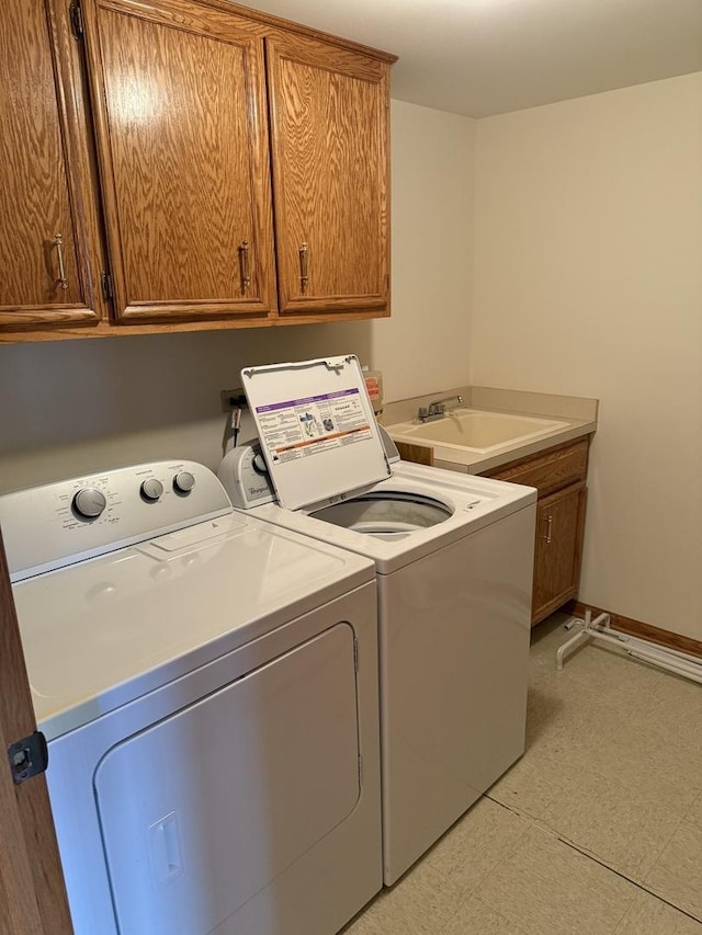 laundry area featuring cabinets, separate washer and dryer, and sink