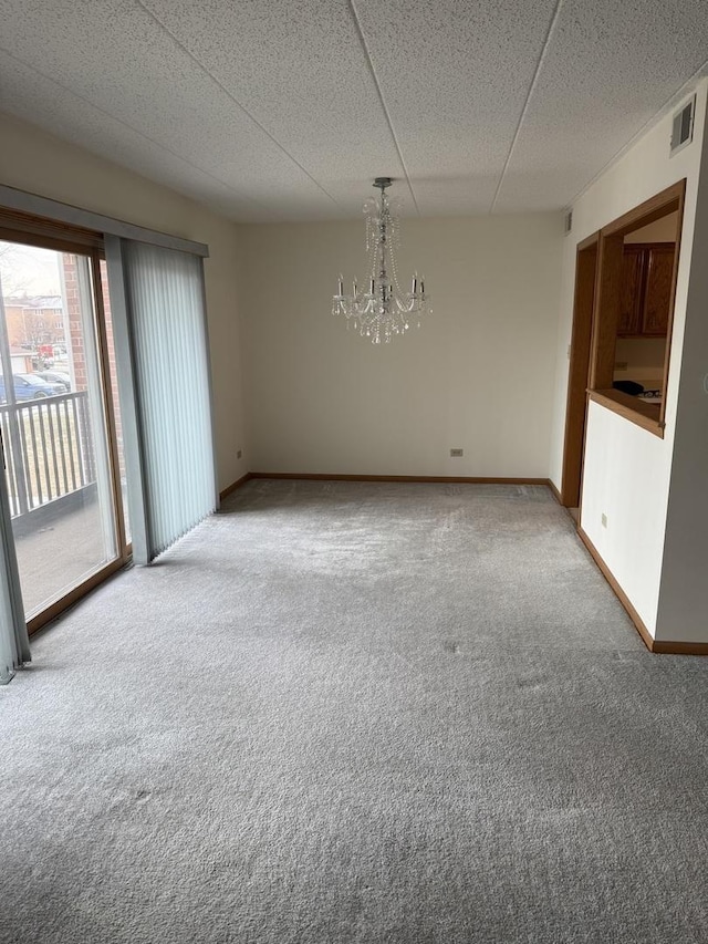 unfurnished room featuring carpet floors, a drop ceiling, and a notable chandelier