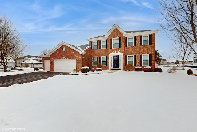 colonial-style house featuring aphalt driveway, brick siding, and a garage