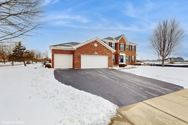 colonial house featuring an attached garage, driveway, and brick siding