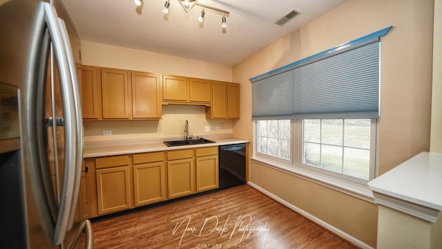 kitchen featuring stainless steel refrigerator, wood-type flooring, black dishwasher, and sink