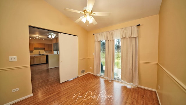 empty room featuring hardwood / wood-style flooring, lofted ceiling, sink, and ceiling fan