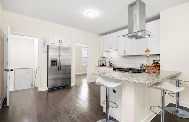 kitchen with stainless steel fridge with ice dispenser, white cabinetry, a kitchen breakfast bar, island exhaust hood, and kitchen peninsula