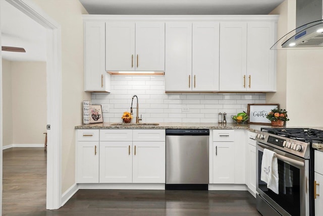 kitchen featuring sink, appliances with stainless steel finishes, wall chimney range hood, light stone countertops, and white cabinets