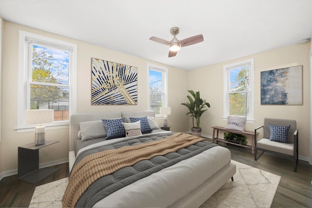 bedroom featuring ceiling fan, dark hardwood / wood-style floors, and multiple windows