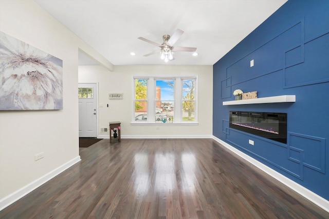 unfurnished living room featuring ceiling fan and dark hardwood / wood-style flooring