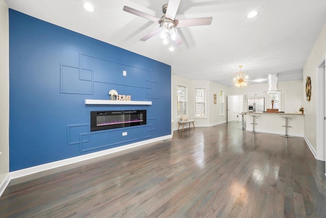 unfurnished living room featuring dark wood-type flooring and ceiling fan