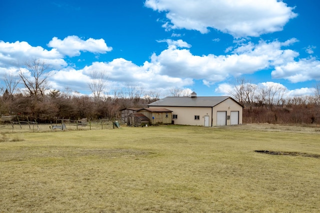 view of yard featuring a rural view, a garage, and an outbuilding