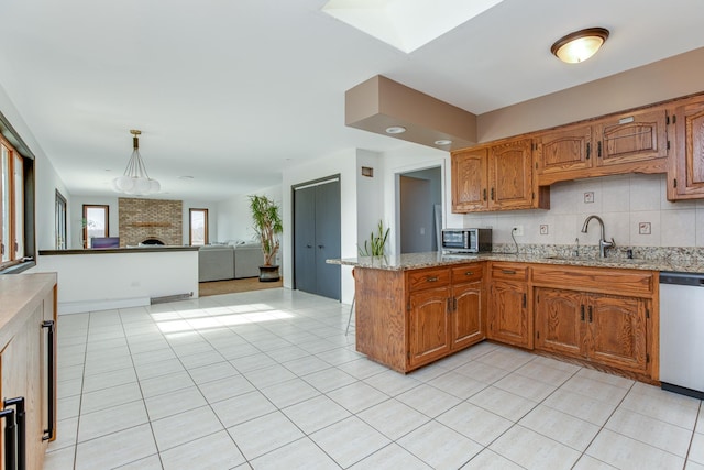 kitchen featuring pendant lighting, sink, stainless steel appliances, decorative backsplash, and kitchen peninsula