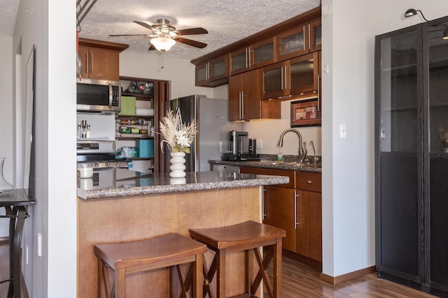 kitchen featuring appliances with stainless steel finishes, sink, kitchen peninsula, dark wood-type flooring, and a textured ceiling