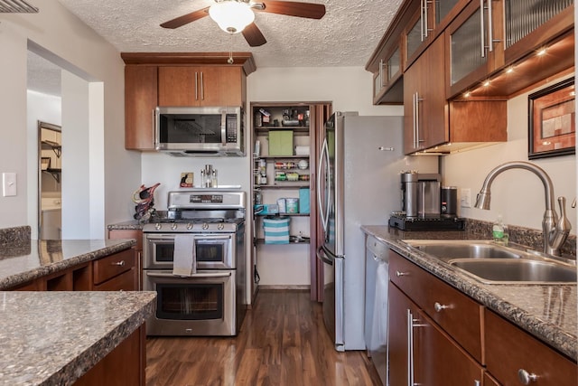 kitchen with sink, dark wood-type flooring, ceiling fan, stainless steel appliances, and a textured ceiling