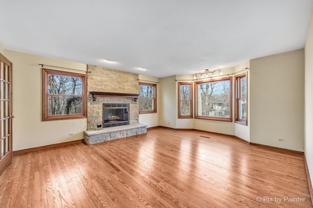 unfurnished living room featuring a wealth of natural light, a fireplace, and light hardwood / wood-style floors