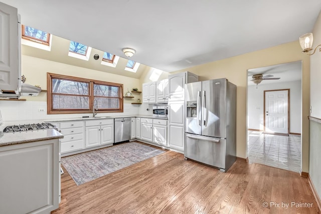 kitchen with tasteful backsplash, white cabinetry, sink, stainless steel appliances, and light wood-type flooring