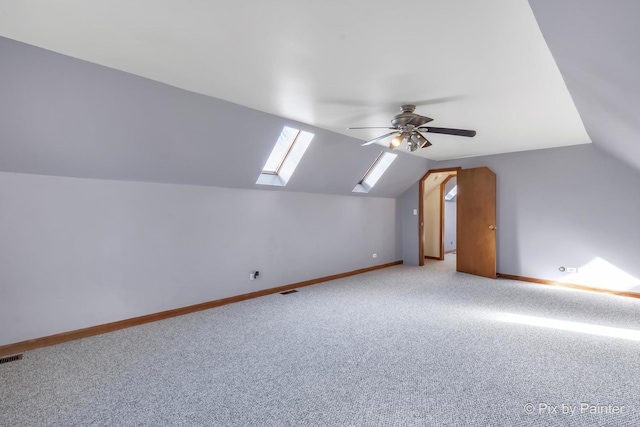 bonus room featuring lofted ceiling with skylight, light carpet, and ceiling fan