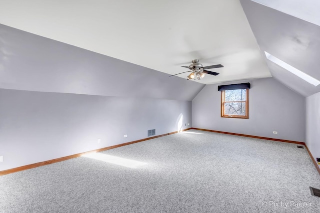 bonus room with ceiling fan, carpet floors, and vaulted ceiling with skylight