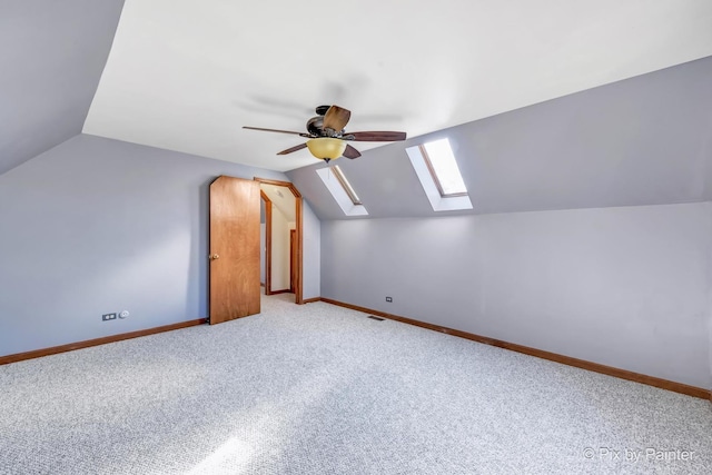 additional living space with light carpet, lofted ceiling with skylight, and ceiling fan