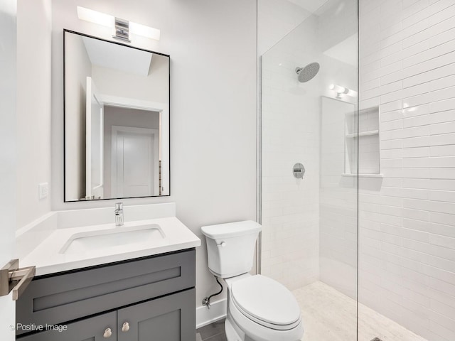 bathroom with vanity, tiled shower, and toilet