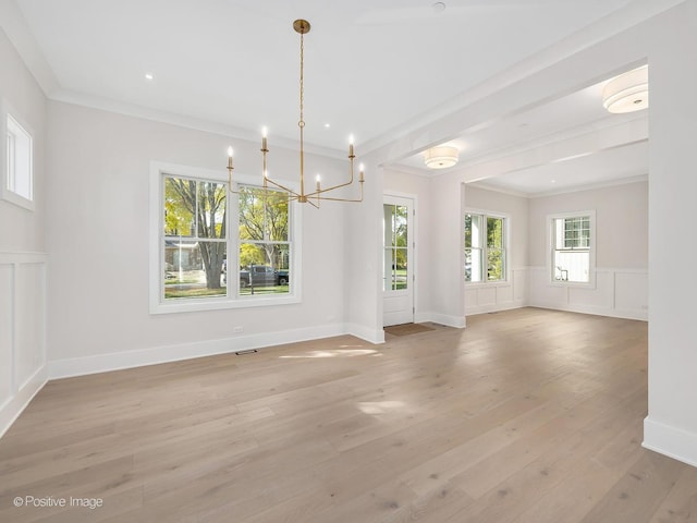 unfurnished dining area featuring an inviting chandelier, crown molding, and light hardwood / wood-style flooring