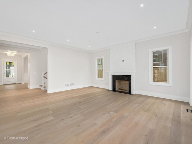 unfurnished living room with ornamental molding, a fireplace, and light wood-type flooring