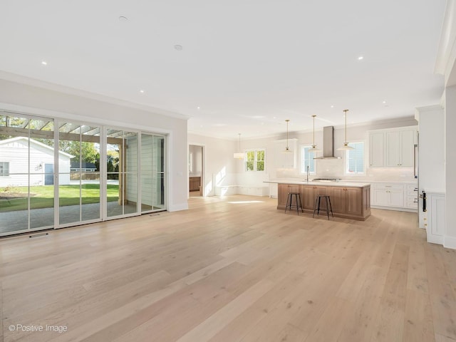 unfurnished living room featuring ornamental molding, sink, and light hardwood / wood-style floors