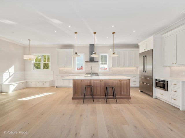 kitchen featuring white cabinetry, appliances with stainless steel finishes, and wall chimney range hood