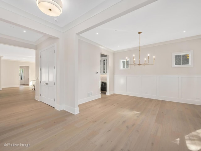 interior space with crown molding, a healthy amount of sunlight, a notable chandelier, and light wood-type flooring