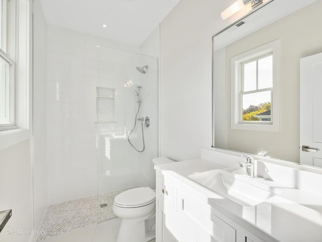 bathroom featuring vanity, a tile shower, and toilet