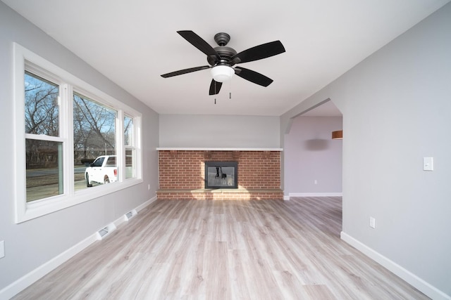 unfurnished living room with a fireplace, ceiling fan, and light wood-type flooring