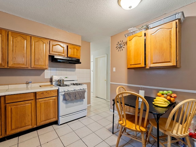 kitchen with tasteful backsplash, light tile patterned flooring, white gas range, and a textured ceiling