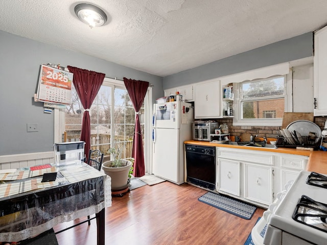 kitchen with black dishwasher, sink, white cabinets, white fridge, and light wood-type flooring