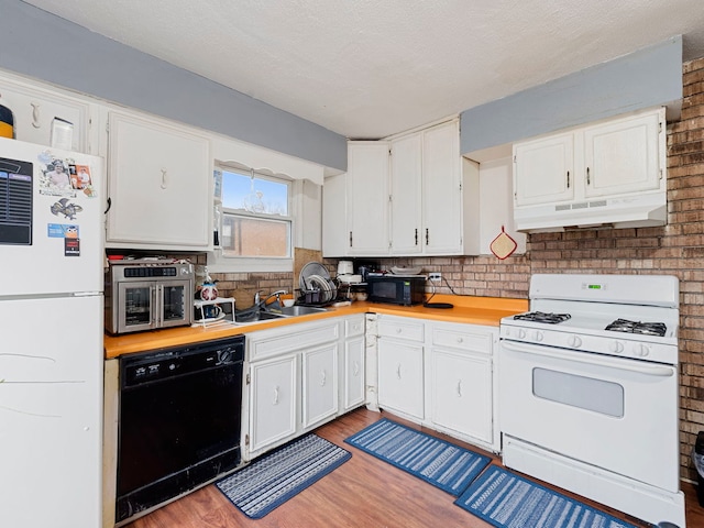 kitchen featuring sink, white cabinetry, backsplash, wood-type flooring, and black appliances