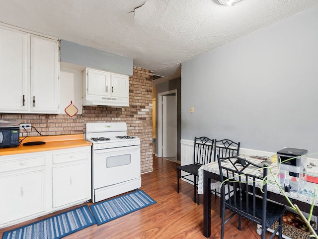 kitchen with dark hardwood / wood-style floors, a textured ceiling, gas range gas stove, and white cabinets