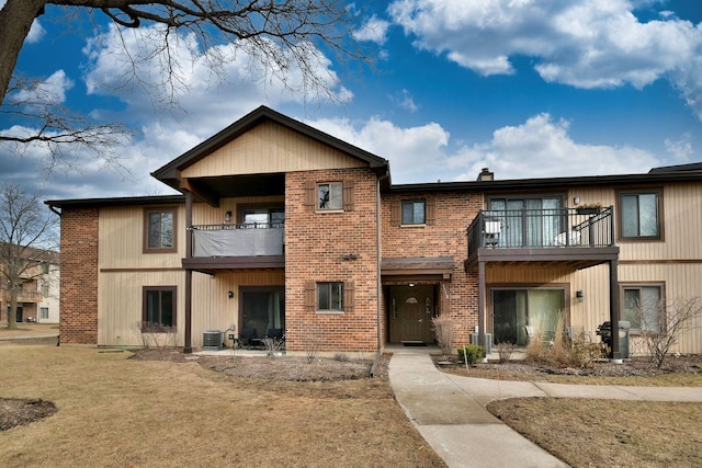 back of property featuring central AC, a balcony, and a yard