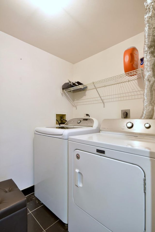 laundry area with dark tile patterned flooring and washing machine and dryer