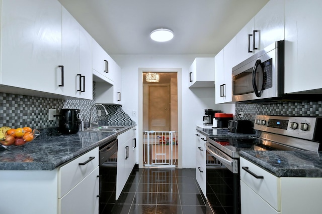 kitchen featuring stainless steel appliances, sink, white cabinets, and dark tile patterned floors