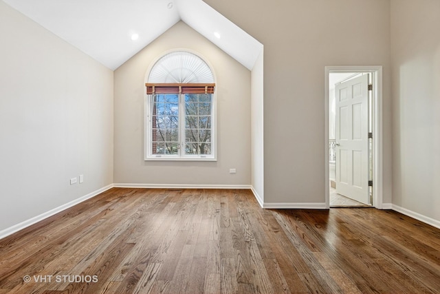 empty room featuring vaulted ceiling, wood finished floors, and baseboards