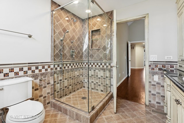 bathroom with tile walls, a shower stall, and tile patterned flooring