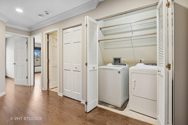 laundry area featuring washer and dryer, wood finished floors, laundry area, and crown molding