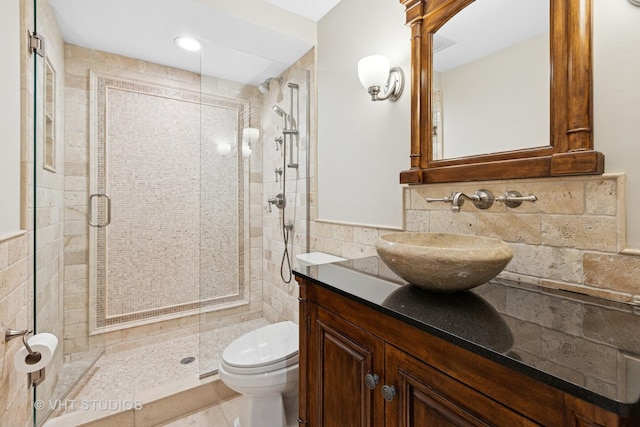 full bath with vanity, a shower stall, toilet, and tile walls