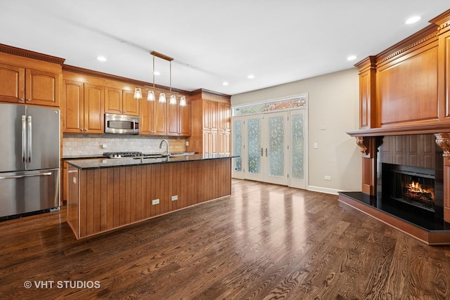 kitchen featuring dark wood finished floors, brown cabinets, a warm lit fireplace, and stainless steel appliances