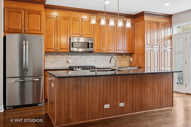 kitchen featuring dark stone counters, brown cabinetry, dark wood-type flooring, and stainless steel appliances