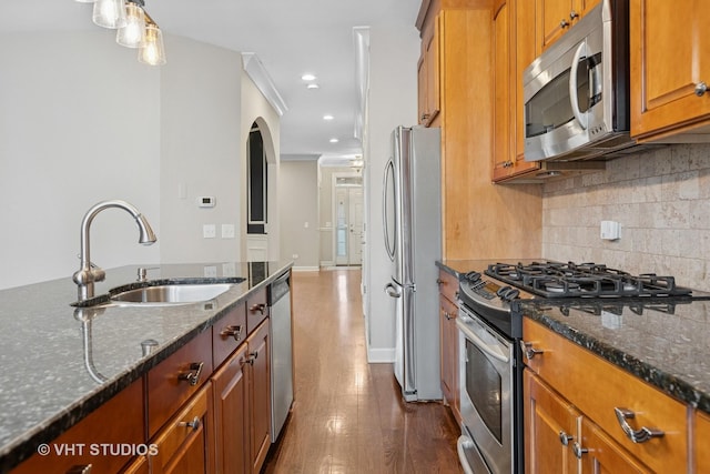 kitchen featuring backsplash, dark wood finished floors, brown cabinetry, stainless steel appliances, and a sink